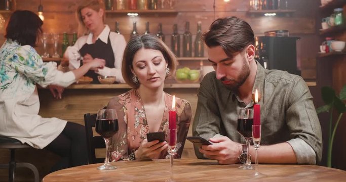 A young careless couple distracted by their smartphones while on a date; The bad effects of social media