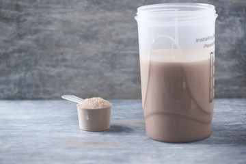 Whey protein shaker and scoop. Sport nutrition. Rustic wooden background. Copy space. 