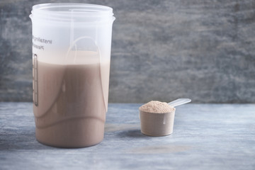 Whey protein shaker and scoop. Sport nutrition. Rustic wooden background. Copy space. 