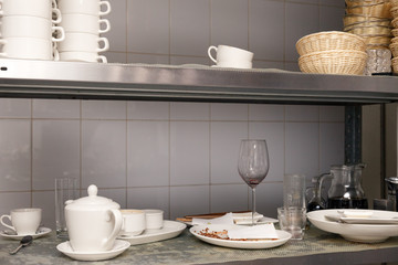 Dirty dishes, wine glasses, plates, cups on metal rack in the restaurant’s kitchen