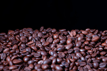 A pile of roasted coffee beans with black background