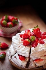 Piece of chocolate meringue cake Pavlova with whipped cream and fresh strawberry