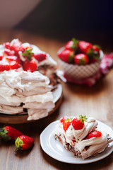 Piece of chocolate meringue cake Pavlova with whipped cream and fresh strawberry