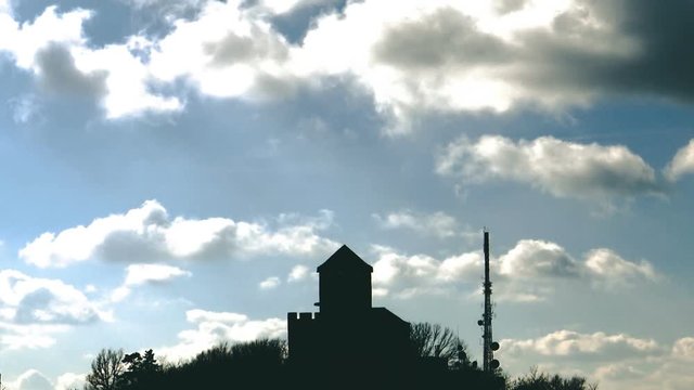 time lapse clouds and blue sky over the tower in the shadow on the top of the hill