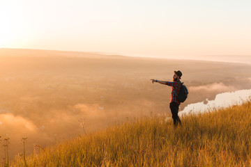 Traveling hipster pointing away in nature