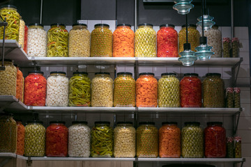 Marinated olives and mixed pickles at San Miguel Market, Madrid. Countertop with different pickling olives in bottles. Green, black and others