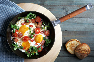 fried eggs with bacon tomatoes and greens, cast iron pan, top view