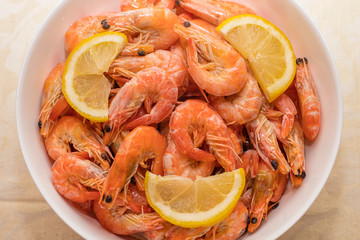 tasty boiled tiger prawns with lemon slices on a white plate. close-up