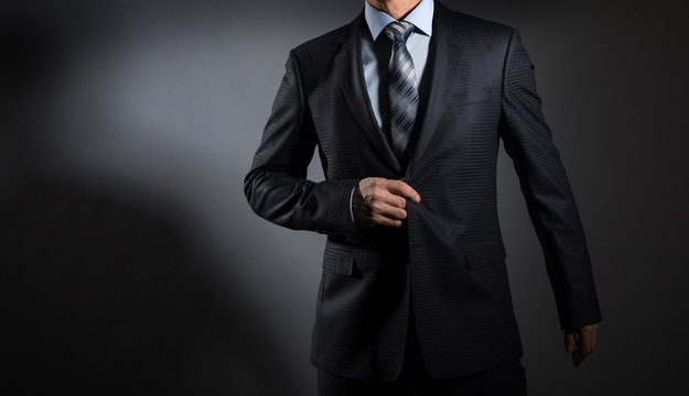 A man in an elegant suit on a dark background. Men's fashion.