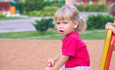 Active little Caucasian girl in a red t-shirt and with tails on playground - closeup shot