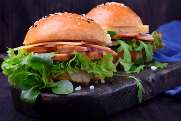 Sandwich with arugula salad, brisket and cheese on a black board
