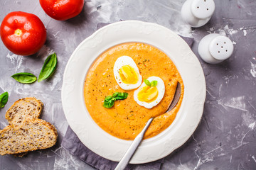 Homemade Spanish salmorejo with egg in white plate, top view.