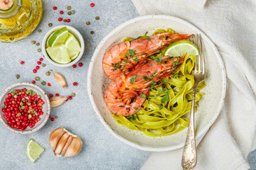 Fried king prawns with garlic, pepper, lime and parsley (cilantro). Large shrimp. Langoustine. Delicious dinner with pasta tagliatelle of spinach. Selective focus