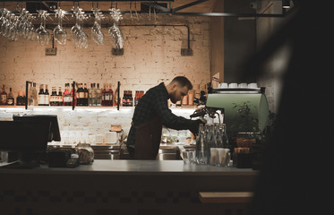 Barista at the restaurant bar counter.Portrait of a bartender with a job in a cozy restaurant.Owner...