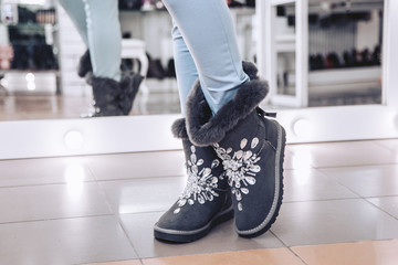 Girl try on winter boots with natural fur in a shoe store