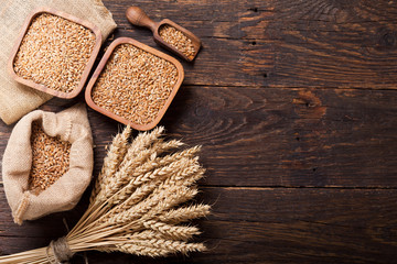 grains and wheat ears on a wooden table - obrazy, fototapety, plakaty