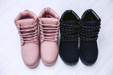 Women's winter boots of pink and black color on a white wooden background.
