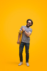 Smiling hipster with skateboard pointing away