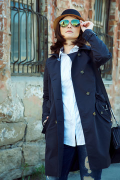 outdoor portrait of a stylish woman in raincoat, hat and sunglasses