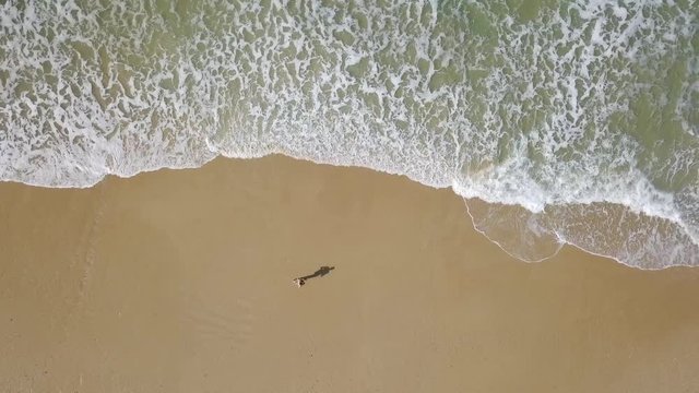 Young fit men during a morning run on the beach - Aerial follow footage.