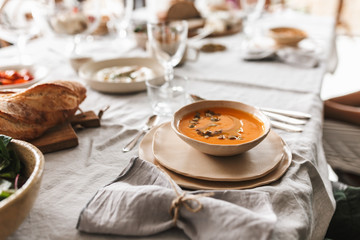 Close up bowl of cream pumpkin soup on table full of food on lunch in cozy cafe