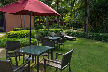 the basketry chair, table and red umbrella set in the garden, in the relax area.