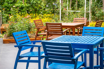 wood blue and brown deck, chair and table set in the garden with colorful flower field background.
