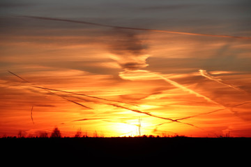 The last rays of the sun at sunset against the orange winter clouds