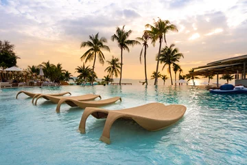 Foto op Plexiglas luxe zwembad met uitzicht op zee en stoel in hotelresort met zonsopgangtijd © arnonphoto