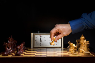 Detail of chess competition. Mans hand making the first move in a chess game, moving the pawn one field forward. Selective focus