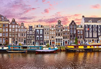 Deurstickers Amsterdam Amsterdam, Nederland. Drijvende huizen en woonboten en boten bij kanalen door banken. Traditionele Nederlandse dansende huizen tussen bomen. Avond herfst straat boven water roze avondrood met wolken.