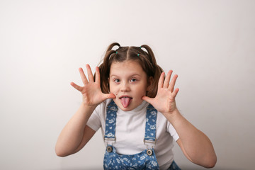 funny girl child with grimaces, shows tongue