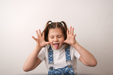 funny girl child builds faces, shows tongue