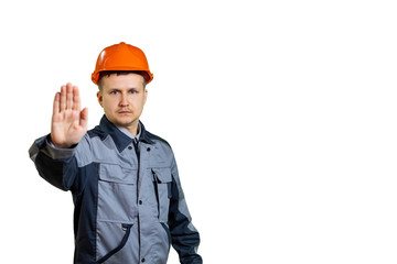 Builder engineer in a helmet palm prohibits gesture. Focus on the working man. Isolated