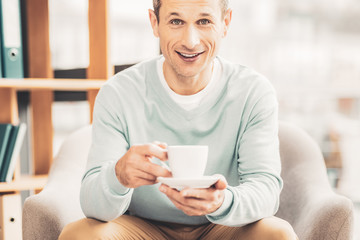 Beaming grey-eyed man enjoying his time at home
