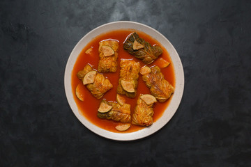Indian cabbage rolls in curry sauce on a black.