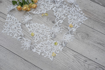 wooden background with spring flowers roses and lace ribbon. Happy womans day. The texture of lace on wooden background.