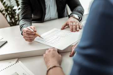 Man with a watch on his hand showing the place for signature to the employee