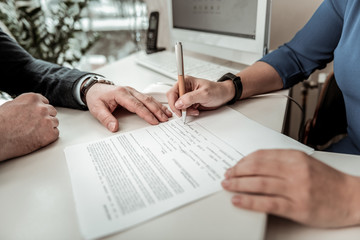 Woman in a blue shirt putting her signature on a document with job offer