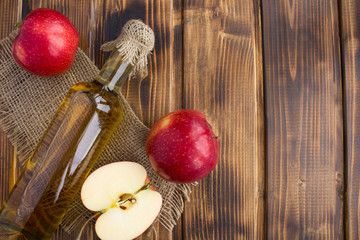 Apple vinegar cider in the glass bottle on the rustic wooden background.Top view.Copy space.