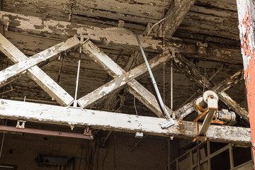 Large wooden beams supporting a tattered ceiling in an abandoned factory
