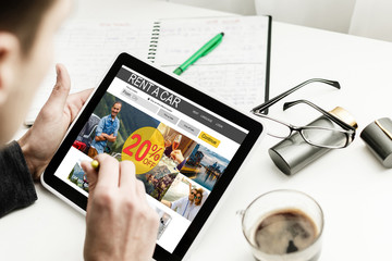 Man holding a tablet renting a car and a credit card
