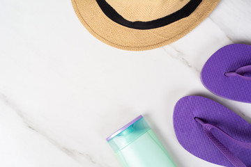 Close-up of a hat, flip flops and sunscreen.
