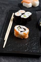 Sushi Set sashimi and sushi rolls served on stone slate 