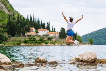 woman jumping on cliff and looking at sea