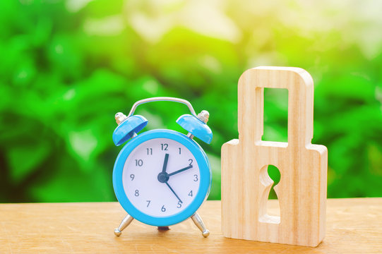 Blue alarm clock and padlock. Non-durable protection time-tested protection and stability. Saving time. The concept of a temporary ban, freezing, Temporarily unavailable, restricted. Selective focus