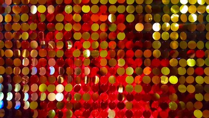 Close up gold sequins reflective background with purple, red, white color light.