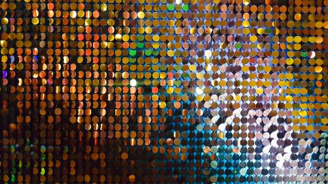 Close up gold sequins reflective background with blue, red, green, purple color light.