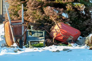 Wheel barrows and garden seat in the winter snow
