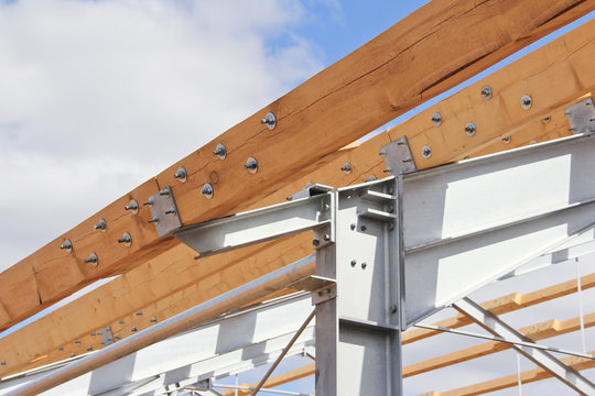 Wooden beams on the metal frame. The design of the new roof. The use of metal and wood in construction.